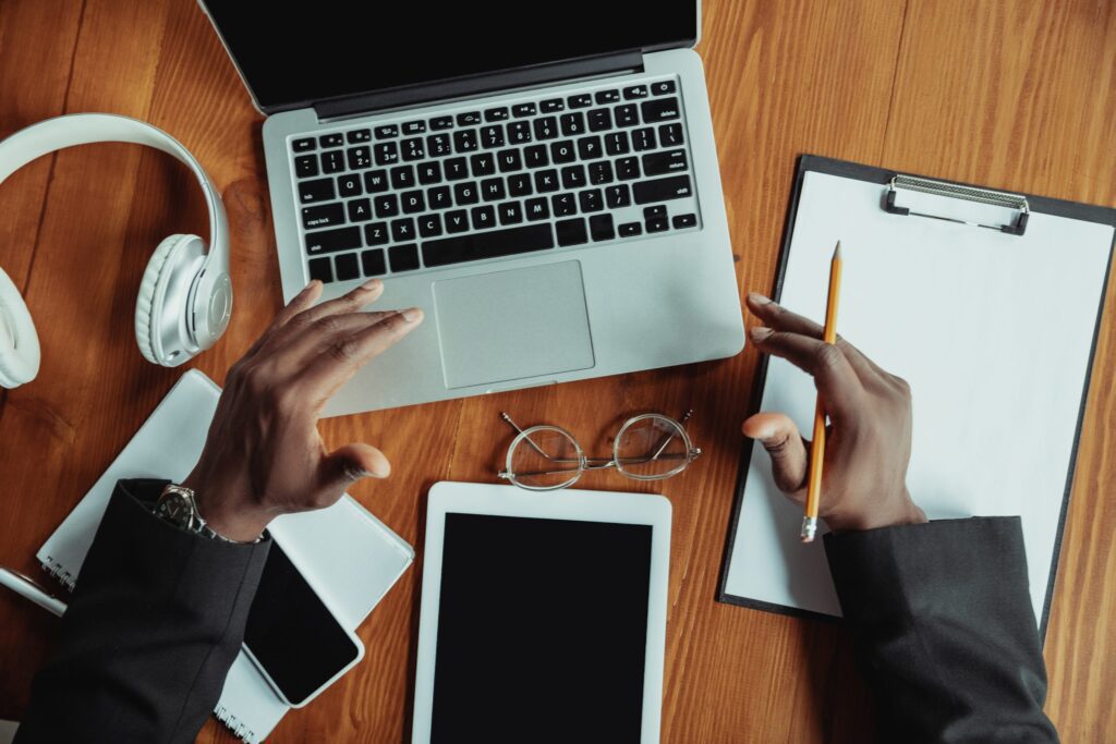 empreendedor mexendo em notebook em uma mesa na qual também se encontram um par de fones