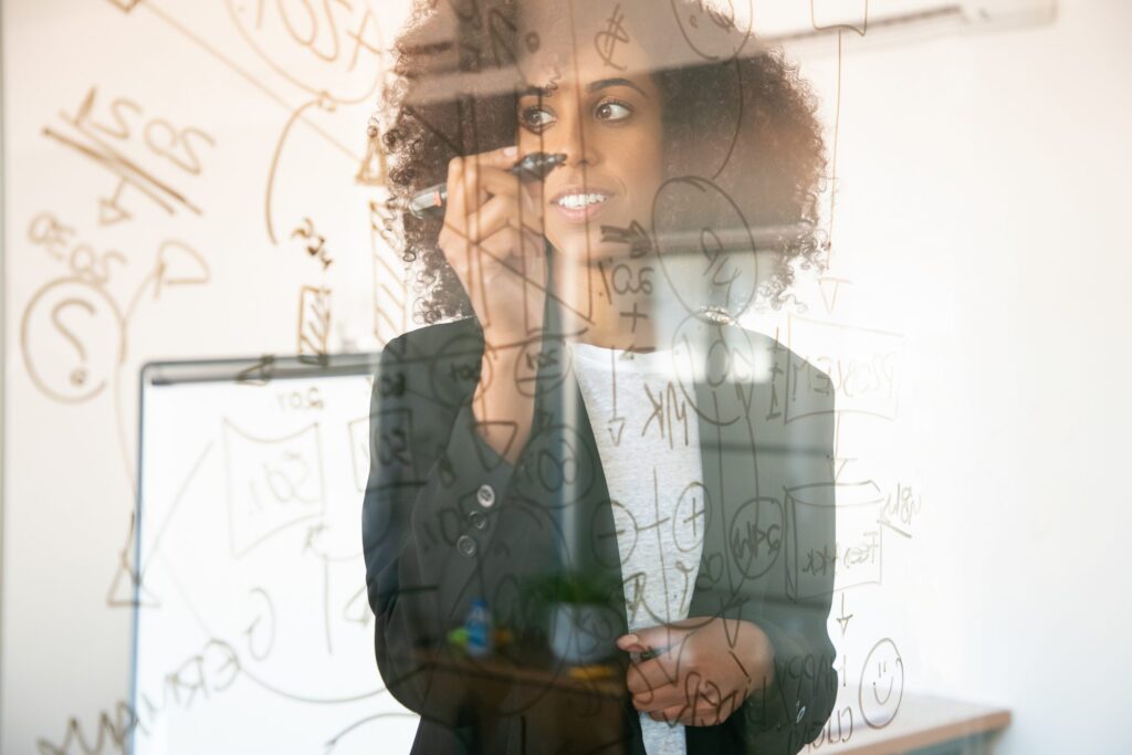 Jovem mulher empreendedora escrevendo em quadro transparente